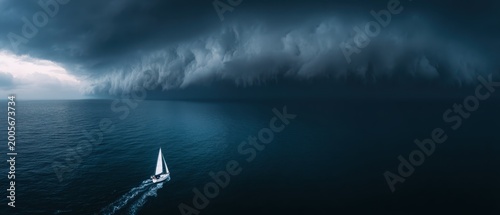 Aerial drone view of white sailboat on dark sea under massive approaching storm clouds