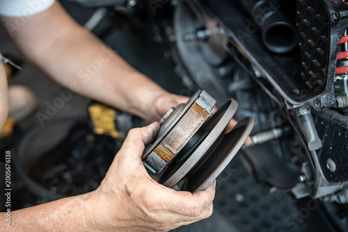 Professional mechanic holding a motorcycle rear clutch pulley assembly for CVT system maintenance.