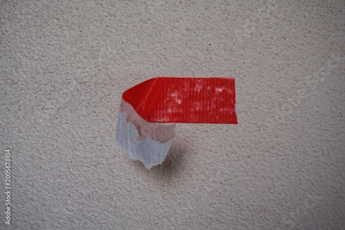Tablou pe pânză Conceptual Image of Peeling Red Duct Tape on a Textured Wall Surface