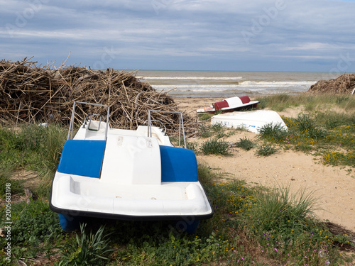 Pedalò abbandonato e detriti su una spiaggia deserta