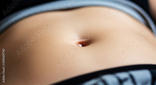 Close up of a human navel with soft skin texture and grey waistband abdomen belly