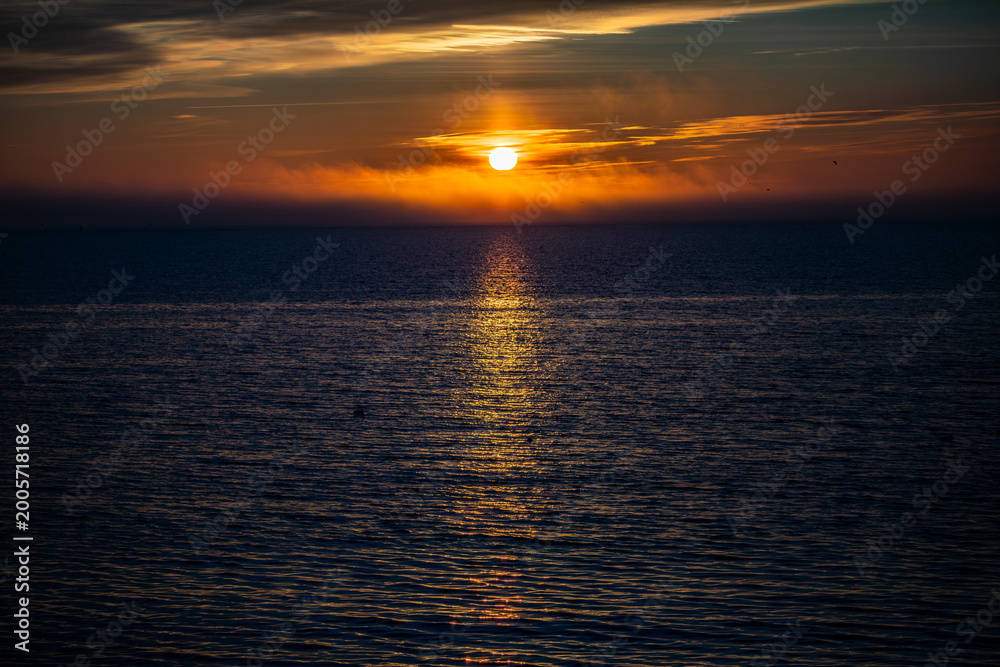 Fototapeta premium A bright sea sunset with a bird-shaped sun in the sky