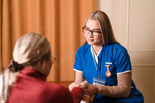 Schilderij op canvas Nurse assists patient during consultation in a medical setting with warm colors