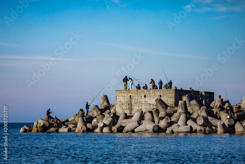 Foto Fishermen on a concrete breakwater by the sea on a cool day