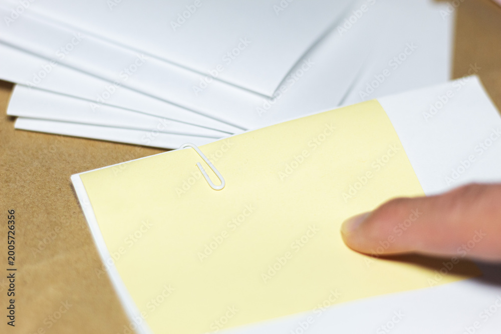 Obraz premium A finger pointing at a blank sticky note on top of a stack of documents; a visual concept of review or pre-marking in a document-handling environment