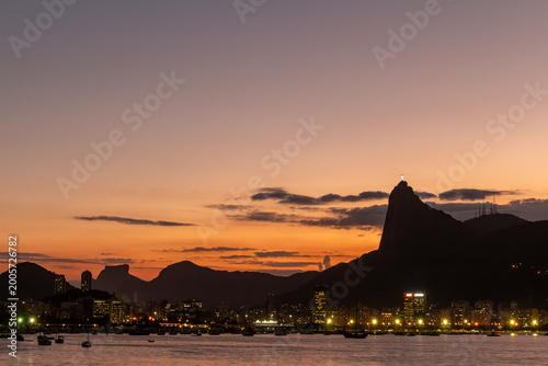 Fotografie Pôr do sol no Rio de Janeiro com Cristo Redentor em silhueta e à beira da baía d