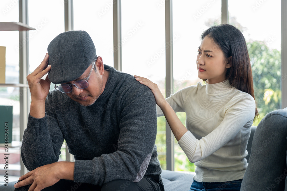 Fototapeta premium Elderly father or Grandparents illness sick struggling with stress and depression, while his adult daughter gently comforts and supports him, providing emotional care and encouragement