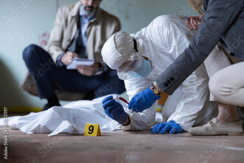 Fotografía Forensic team examining a crime scene, collecting blood samples and documenting