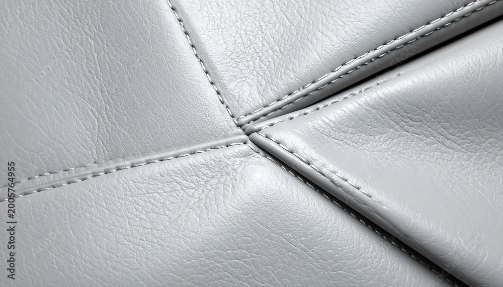 Fototapeta premium Close-up of four stitched leather panels with a central seam intersection, showing texture and detail. The color is a light gray