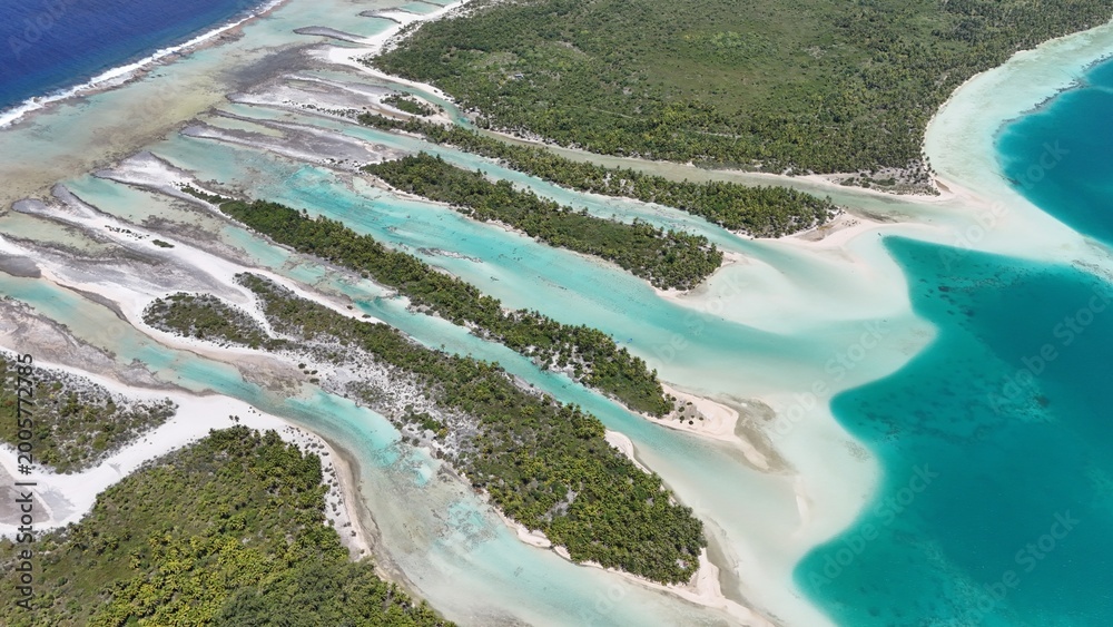 Fototapeta premium Aerial drone shot of turquoise lagoon in French Polynesia with tropical island, clear blue water and luxury travel destination