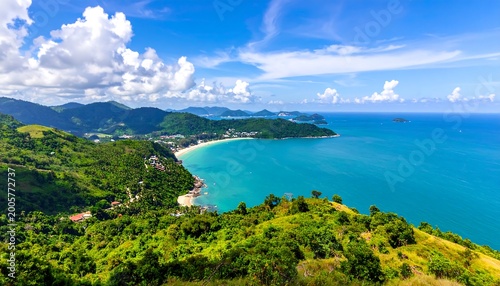 Scenic landscape featuring a vibrant coastal scene under a bright, sunny sky. Green hills meet turquoise ocean with a sandy beach in the distance