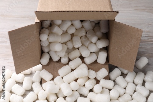 Φωτογραφία Cardboard box with styrofoam pieces on wooden background, closeup