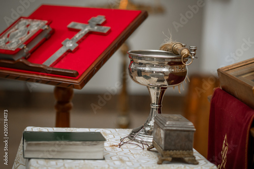 Foto Orthodox Gospel book and silver cross on red velvet lectern in church with icono