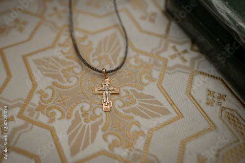 Golden orthodox cross pendant on liturgical embroidery fabric for baptism ceremony in church