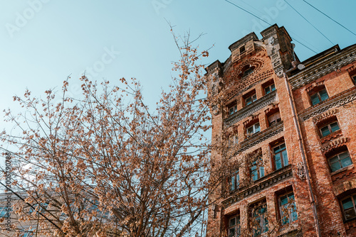 Eclectic historic building with intricate brickwork amid dry autumn branches 