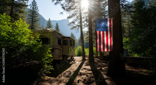 Sunlit american flag waving beside rustic rv cabin in serene mountain forest at dawn