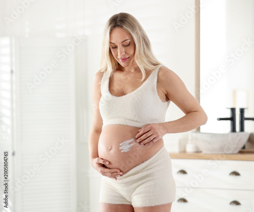Pregnant woman applying cream onto her belly at home Free Download Pregnant woman applying cream onto her belly at home - GFXLoad