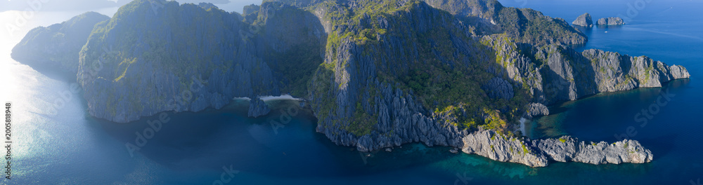 Fototapeta premium Dramatic limestone islands rise in Bacuit Bay, El Nido. This scenic area in the Philippines is a popular vacation destination due to its beautiful coral reefs, beaches, and hidden lagoons.