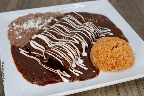 Bild auf Leinwand Hearty plate of enchiladas smothered in mole sauce with beans, and rice to satis