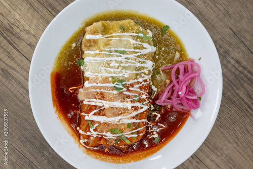 Overhead view of hearty wet burrito smothered in red and green sauce split in half to satisfy that urge for a Mexican food meal