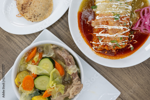Hearty feast of Mexican food on the table family style consisting of a wet burrito, gordito, and beef soup