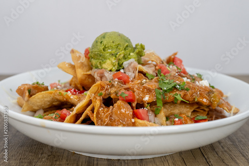 Hearty plate of nachos smothered in guacamole, beans, and feta cheese to satisfy that urge for a Mexican food meal
