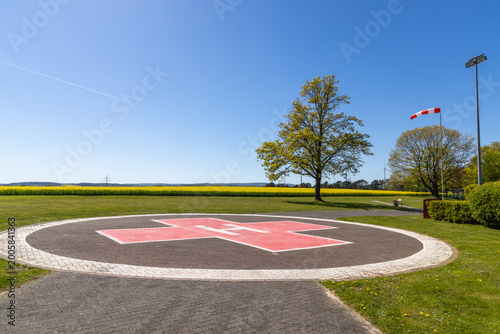 Foto Helicopter landing port in the landscape near a hospital with yellow rape field