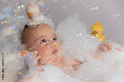 Foto Baby enjoying a bubble bath playing with rubber ducks