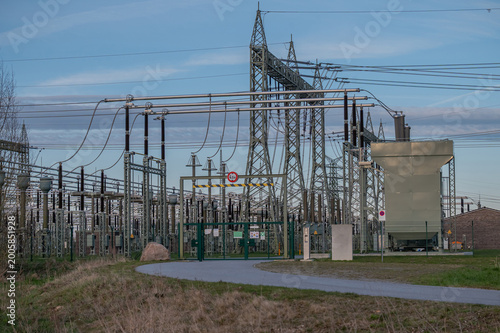 Fotografia Electrical substation with complex high-voltage infrastructure, including transformers, transmission lines, and steel lattice structures