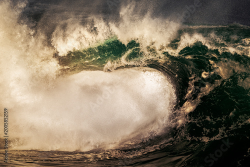 Fotografie Large powerful ocean wave breaking over shallow reef in dramatic golden light along the New South Wales coastline, Australia