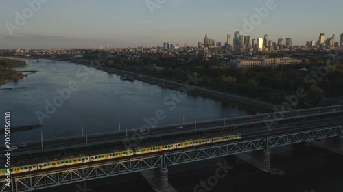 Breathtaking drone shots from Warsaw's Praga side of the Vistula capture sunset glow over the skyline. Golden light bathes bridges, rivers, and cityscape in warm hues