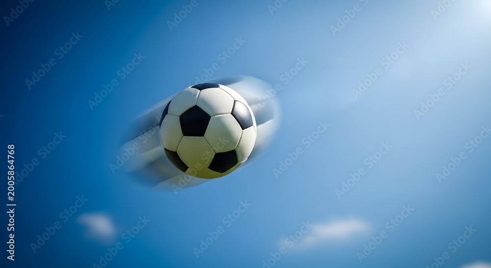 Fototapeta premium A soccer ball in motion against a bright blue sky with motion blur