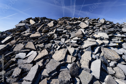 A large pile of broken asphalt under a clear blue sky. Symbolic of road construction, infrastructure renewal, and urban transformation