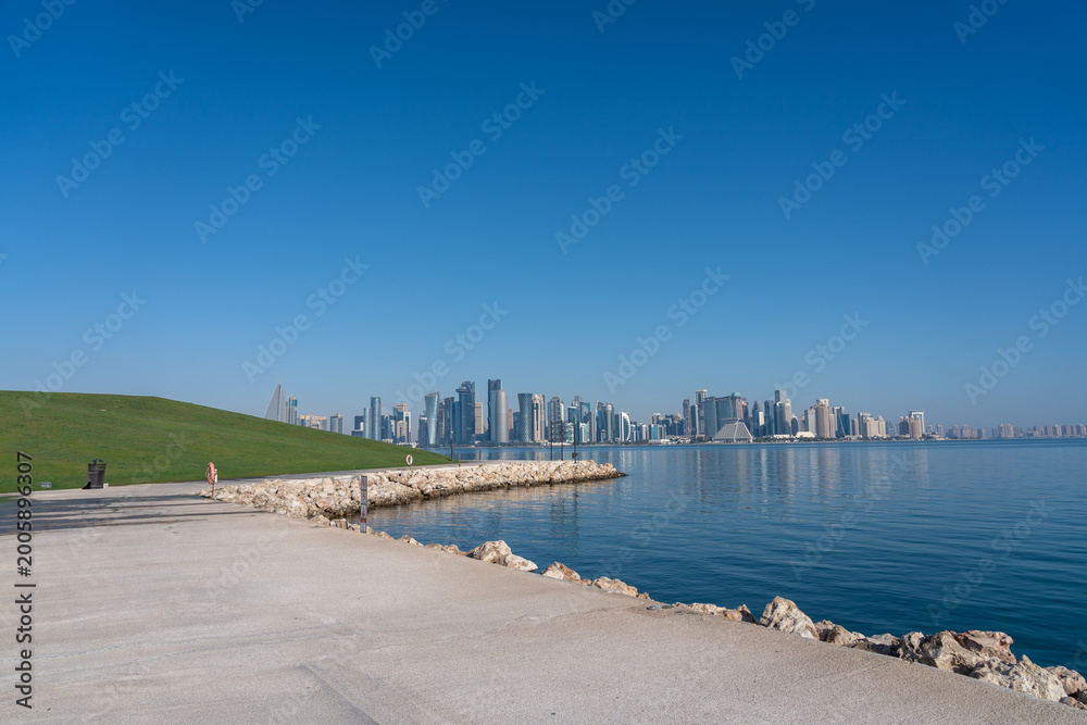 Fototapeta premium Doha MIA Park Promenade with Grassy Mound West Bay Skyline and Walker