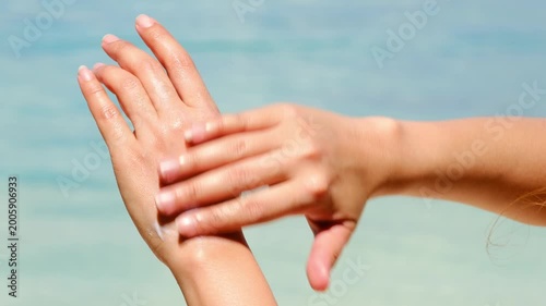 Sunscreen from blue bottle on palm she apply hand and arm with bright sun and blue sky background, skin protection and summer skincare concept	