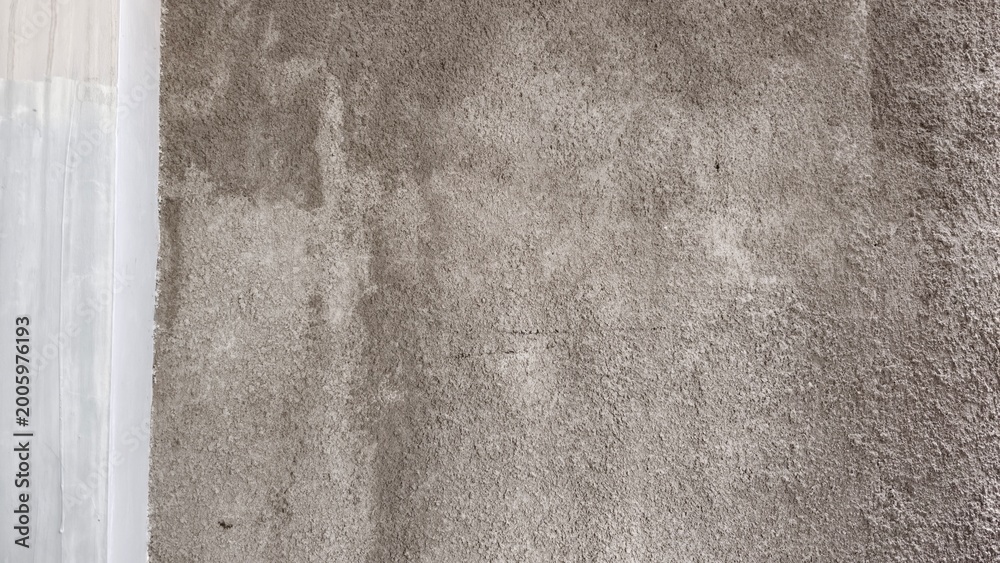 Fototapeta premium Rough grey concrete wall texture with a contrasting smooth white vertical edge.