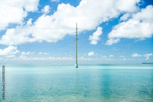Obraz na plátne Electric power pole standing in the shallow sea water under the cloudy sky near the Florida Keys horizon on a bright day