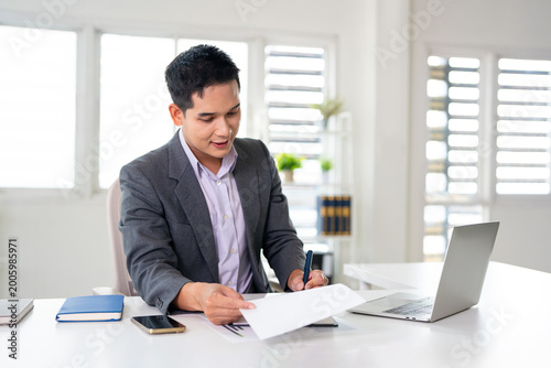 Tableau sur toile A businessman is working in modern office, reviewing documents
