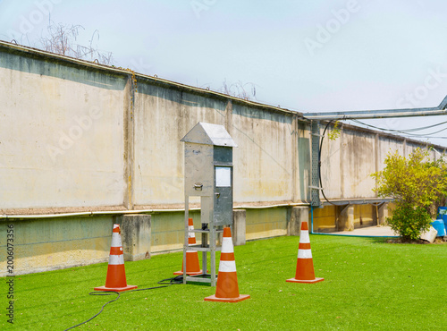 An outdoor environmental air quality monitoring station and sampling device installed on a lawn, secured with orange safety cones for industrial data collection.
