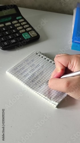The hand uses a pen to write the numbers in the notebook. Accounting, accounting. A woman counts expenses, dead. Payment of taxes