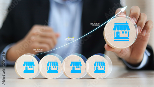Obraz na plátně Businessman's hand chooses wooden toy stack with franchise icon for goal to growth is investment planning financial and branch expansion and management bank loans for marketing franchising