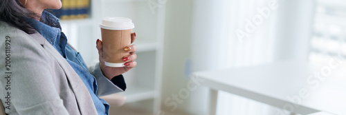 Schilderij op canvas Asian businesswoman holding takeaway coffee cup standing modern office building