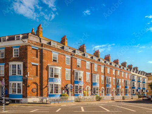 A row of historic red brick Georgian terraced houses decorated with Union Jack bunting (Weymouth, England, United Kingdom)