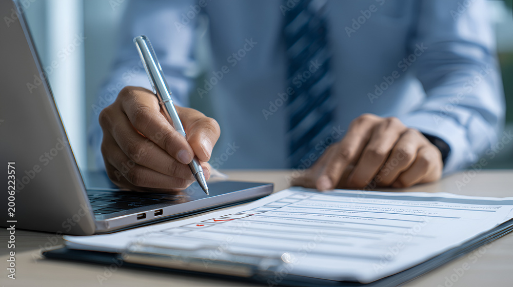 Fototapeta premium ISO certification and quality compliance concept. businessman reviewing audit documents on laptop, focusing on digital checklist, performance validation, and process improvement for standard assurance