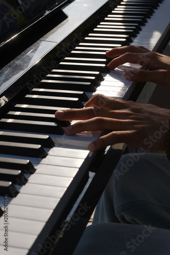 Hands Playing Piano Keys Close-up with Beaded Bracelets and Smartwatch