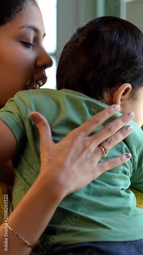 Indian infant sleeping on mother's shoulder while she stands cuddling and comforting baby boy lovingly in warm modern home, showing peaceful bonding, motherhood, affection, and early parenting care