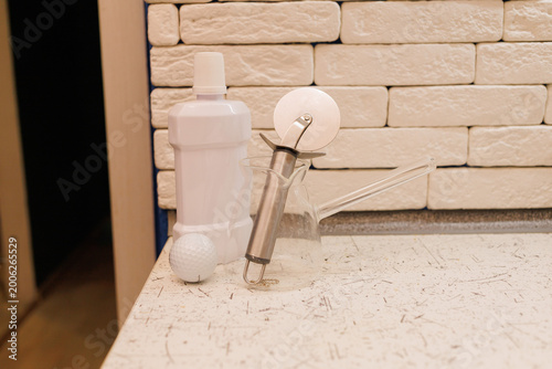 A white bottle, glass container, roller cutter, and golf ball are on a kitchen countertop