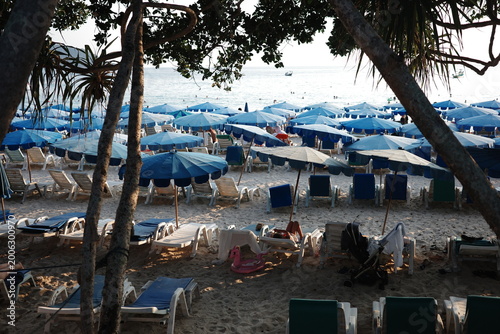 Foto Crowded tropical beach with blue umbrellas and sun loungers