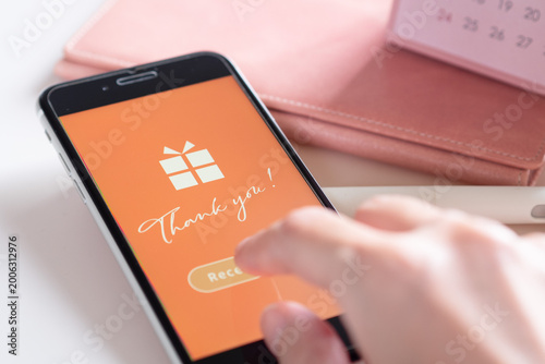 スマホに届いたソーシャルギフト (eギフト) の受け取り画面をタップする女性の手元