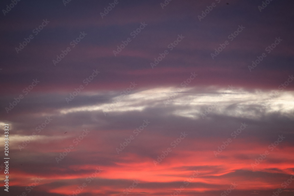 Obraz premium Beautiful sunset sky blending orange, yellow, and gray hues, creating a calm, dramatic atmosphere with soft glowing clouds.